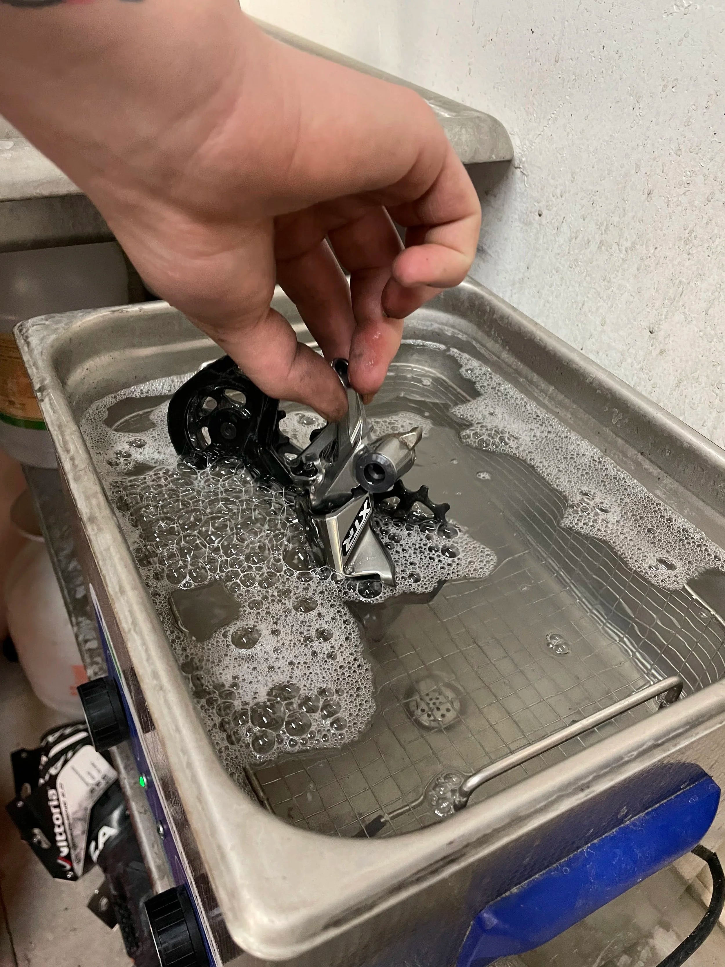 Person cleaning a bicycle chain in a soapy water bath.